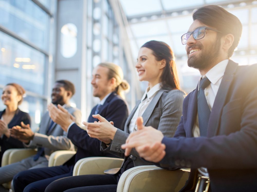 Contemporary business people clapping their hands at conference or other corporate event