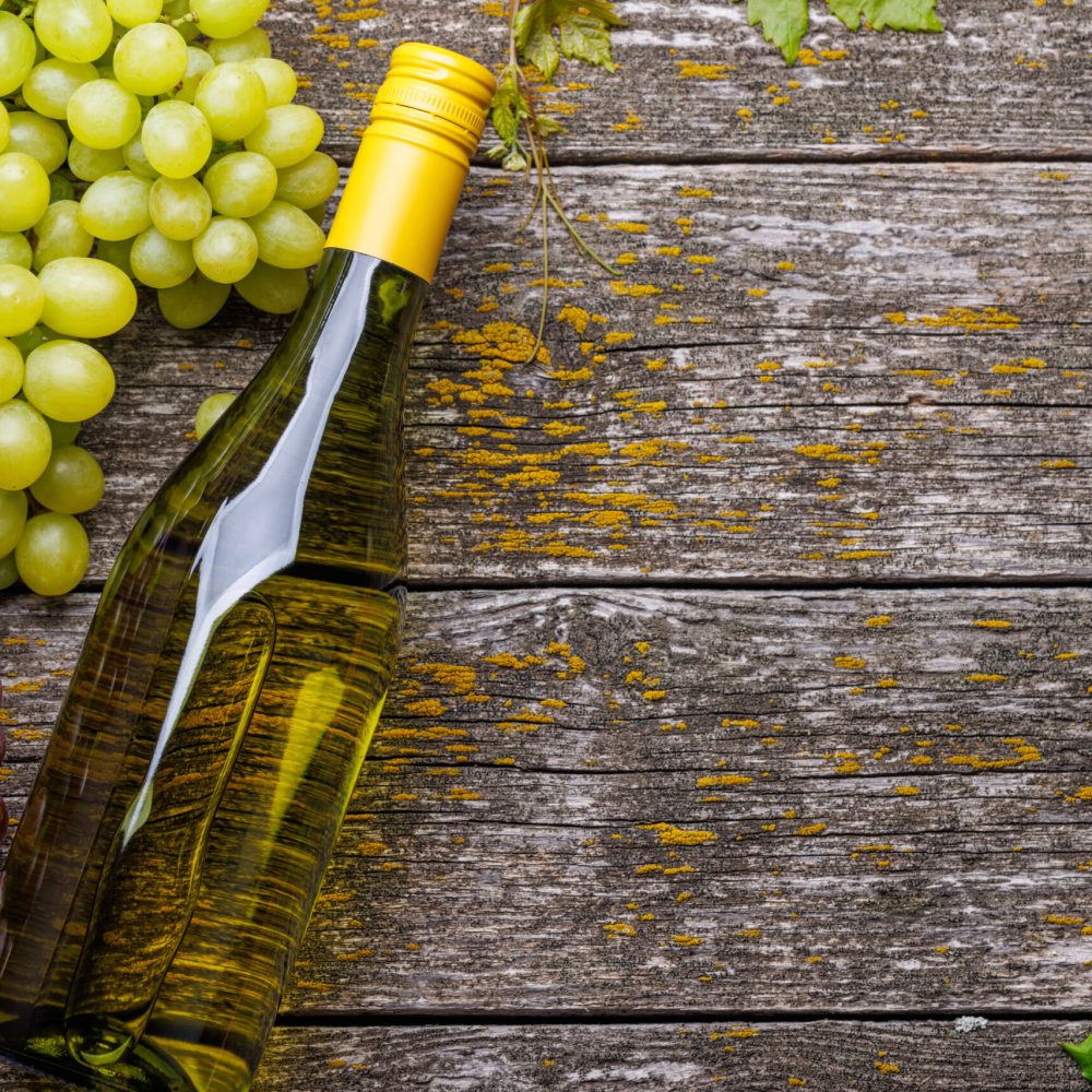 Wine bottle and grape on wooden table. Flat lay with copy space