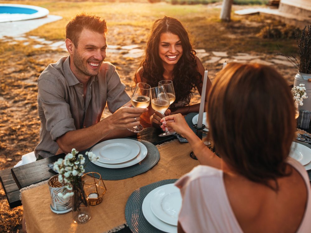 Cropped shot of handsome smiling friends having dinner in the backyard